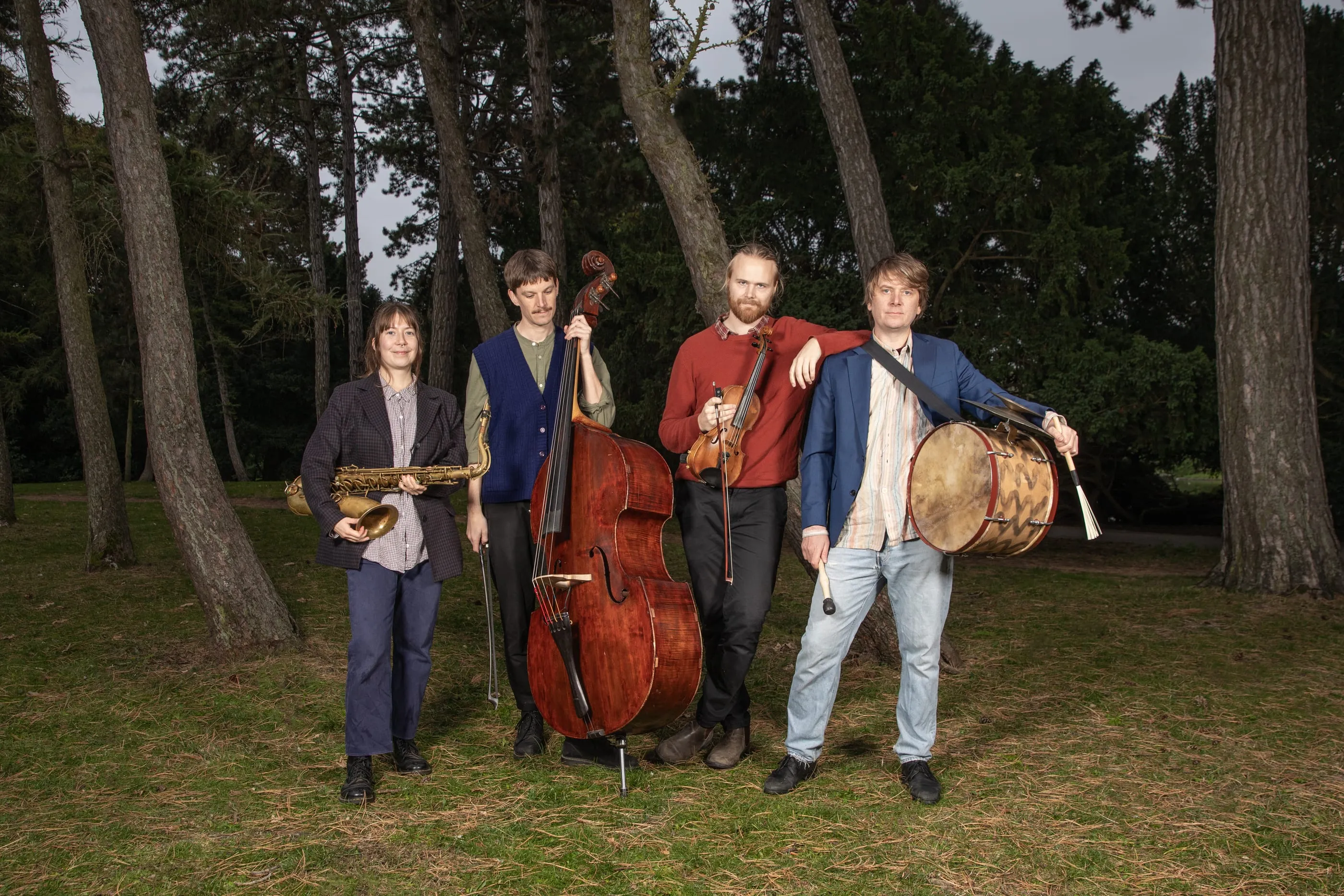 The band with their instruments on a lawn in the forest.